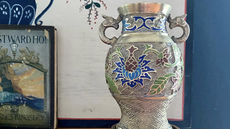 A silver-toned champlevé vase with a floral design and handles