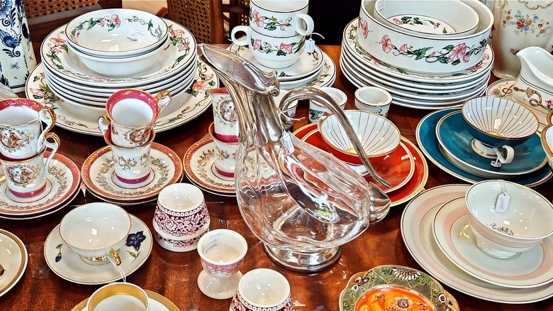 Various chinaware displayed on a wooden table in a vintage shop