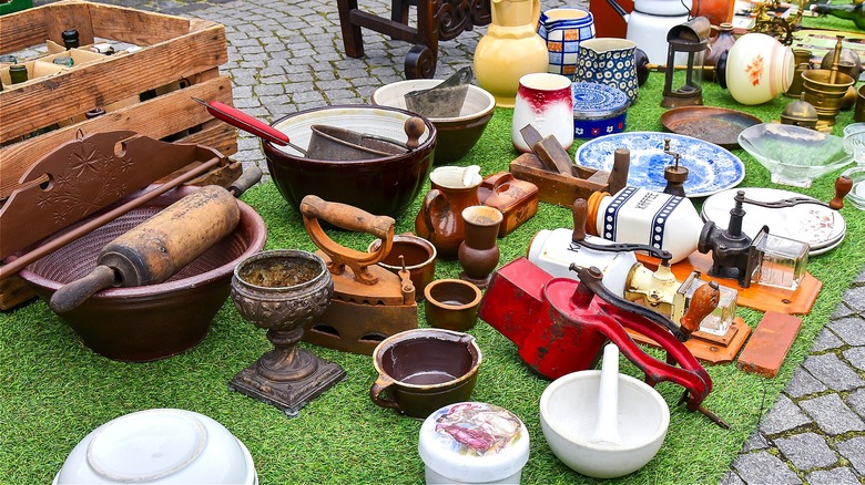 A bunch of antique décor and kitchenware on the ground at a flea market