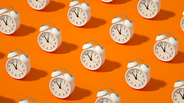 Graphic of rows of alarm clocks against an orange background