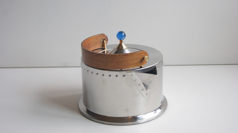 A stainless steel tea kettle with a wooden handle and a blue knob, displayed against a white background.
