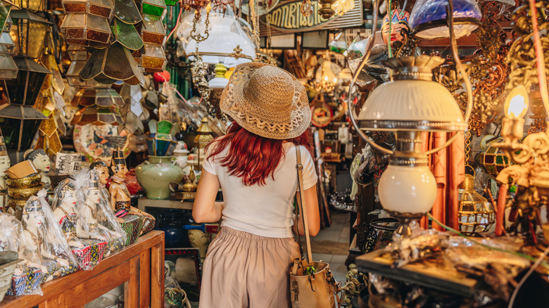 A woman in a crowded vintage store surrounded by lamps