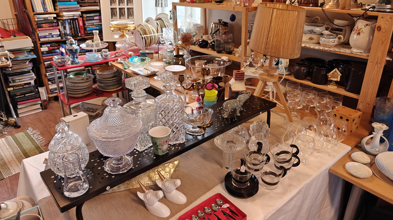 A thrift store with tables of crystal glassware, plates, and home decor.