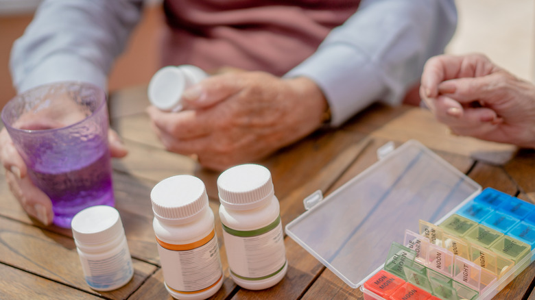 A close up two people holding pill containers and tablets