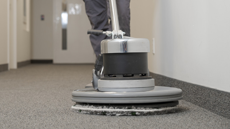 Person cleaning carpeting inside a room