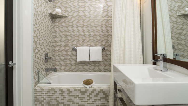 An alcove tub is decorated with a pattern of white and beige tiles