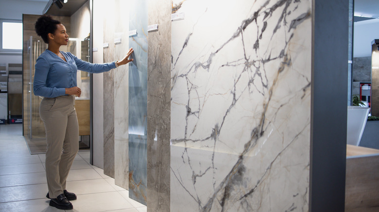 A woman browses a row of large marble slabs in a showroom