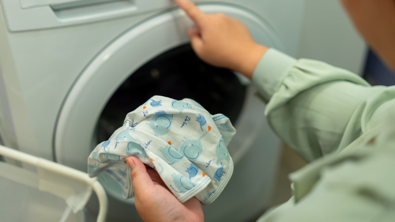 Woman's hand holding cloth in front of washing machine