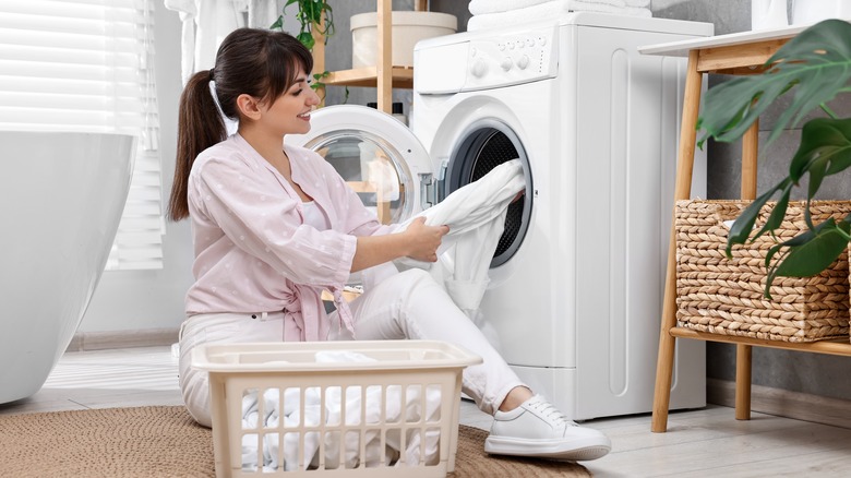 Woman inspecting clothes near washing machine