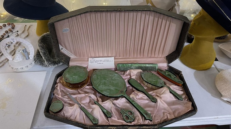 A vintage 1930s or 1940s vanity box with a pink satin interior and green celluloid beauty accessories.