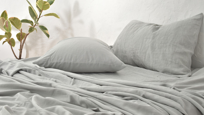 Gray linen sheets on unmade bed