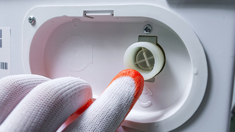 Person pointing to washing machine inlet filter