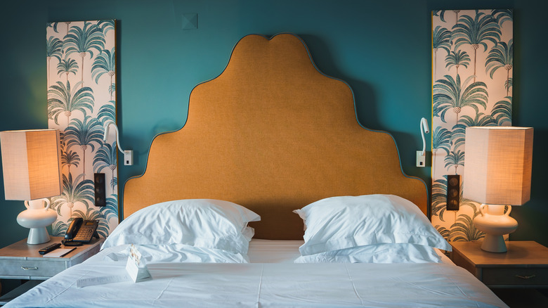 A scalloped, mustard-colored headboard in front of a blue wall