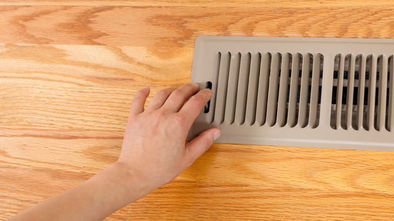 A hand opening or closing a heat vent