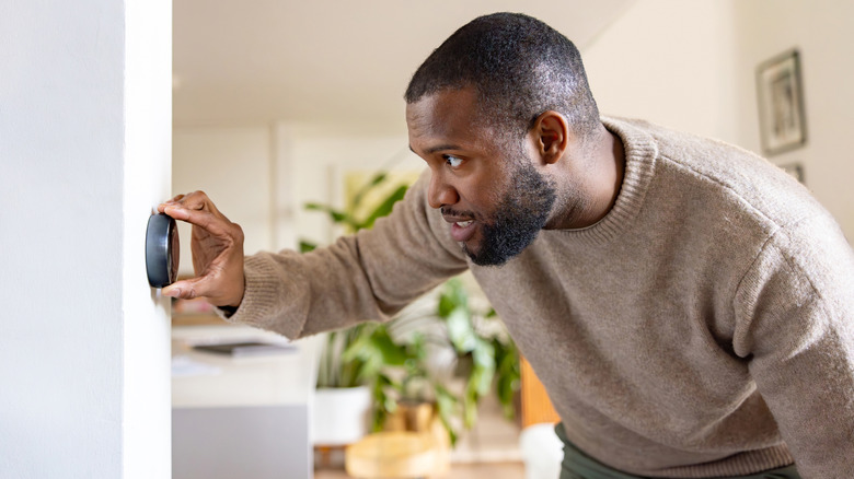 A man adjusting the temperature on a thermostat