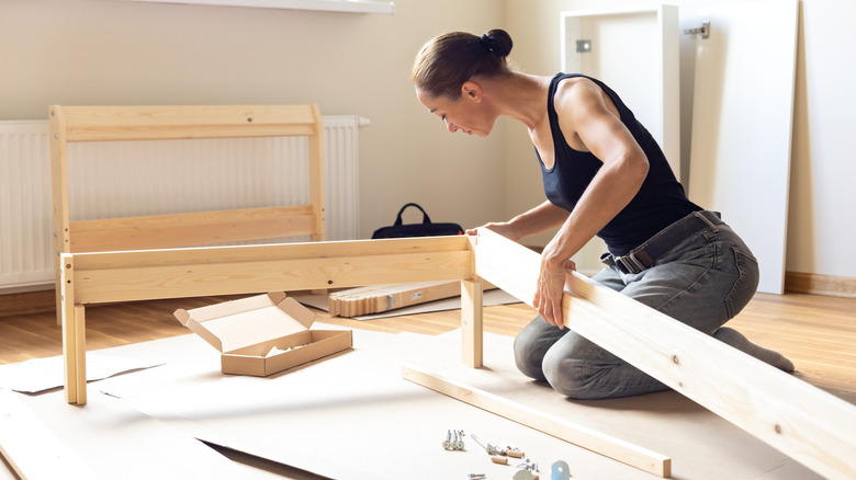 Woman assembling pine wood bed frame.