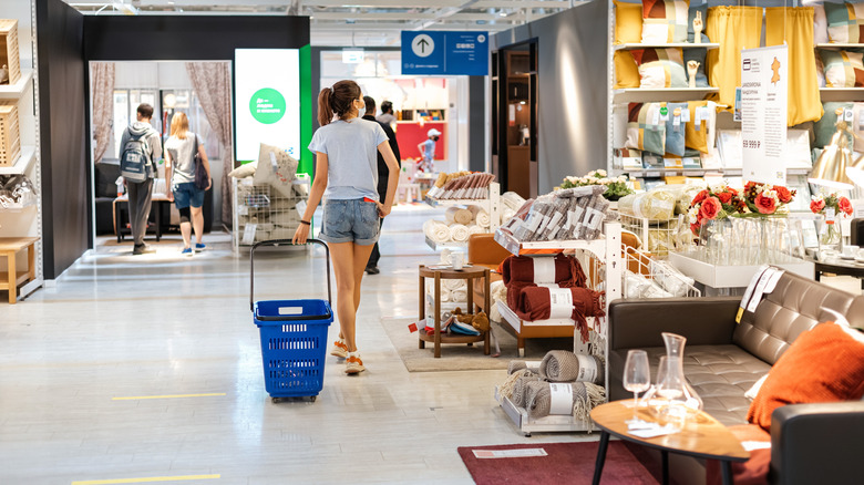 Woman with shopping basket browsing through IKEA.