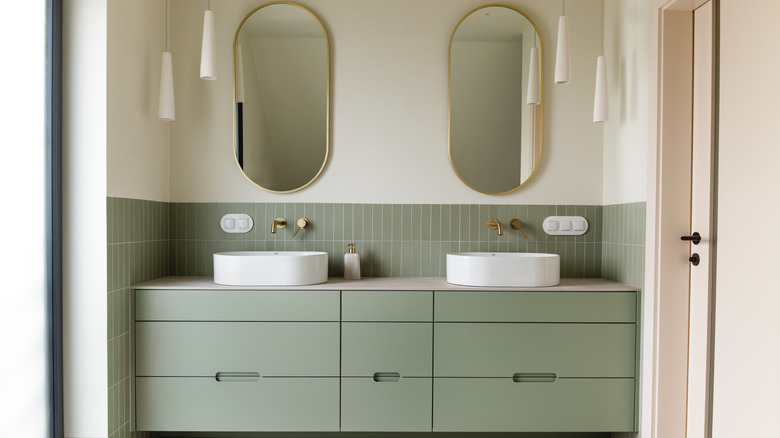 A modern bathroom with sage green cabinets.