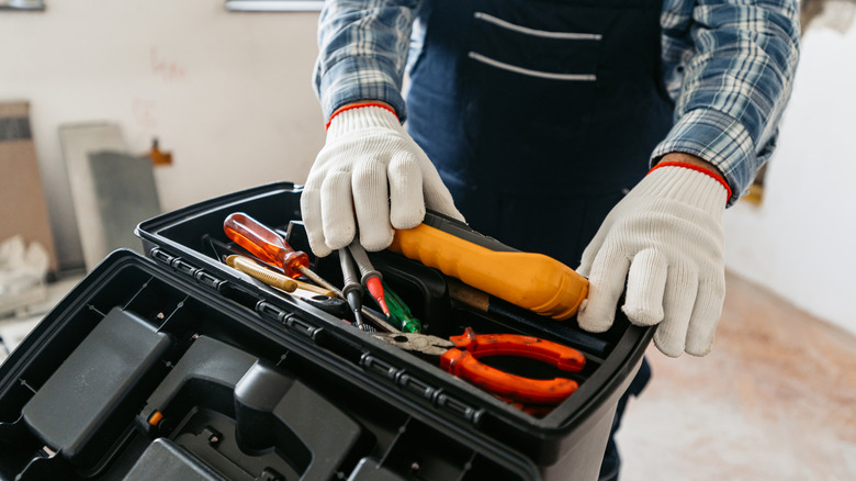 close up of a person with gloves opening a toolbox