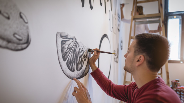 man drawing on white wall 