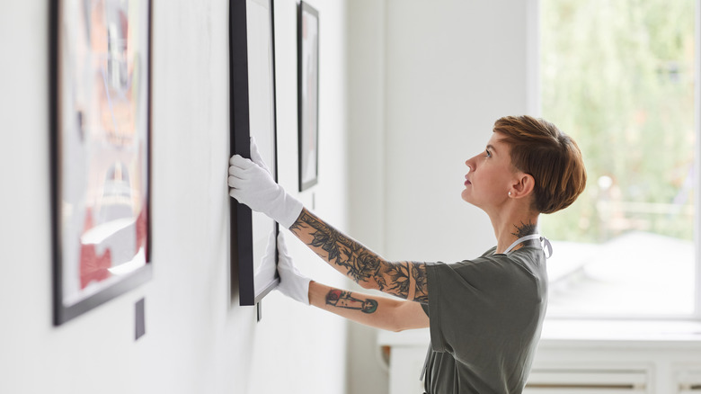 woman hanging frames on wall 