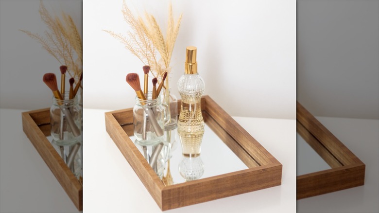Mirrored makeup tray with perfume on it