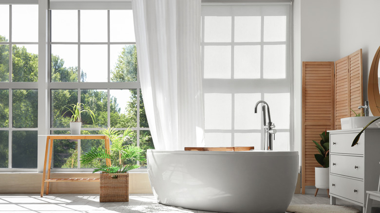 bathroom with a floor length curtain in front of a large window