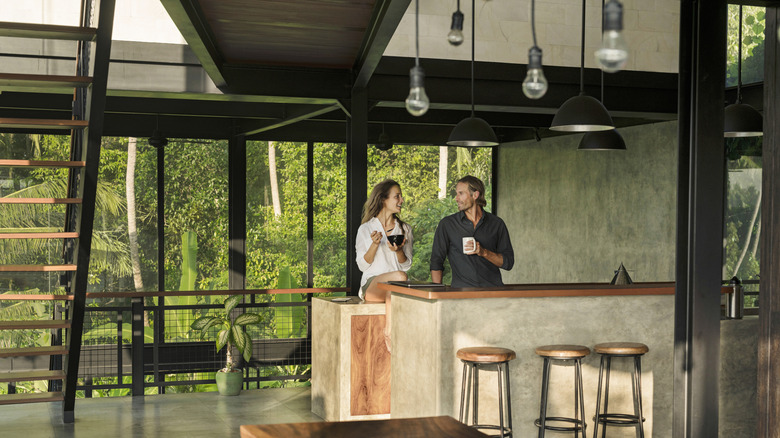 A couple sitting in a kitchen with large windows