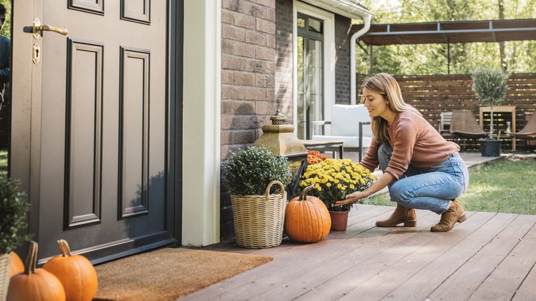 A woman places flowers on the front porch.