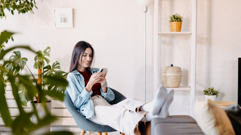 woman looking at her phone with her feet up, surrounded by potted plants