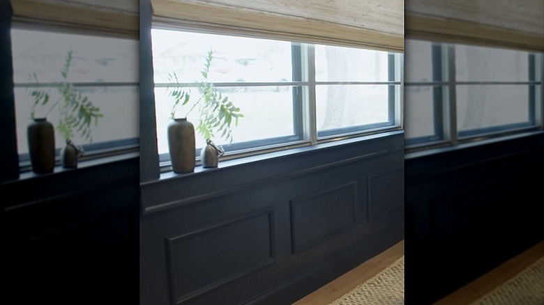 Faux wainscoting made from applied molding on a wall underneath a large window in a home office.