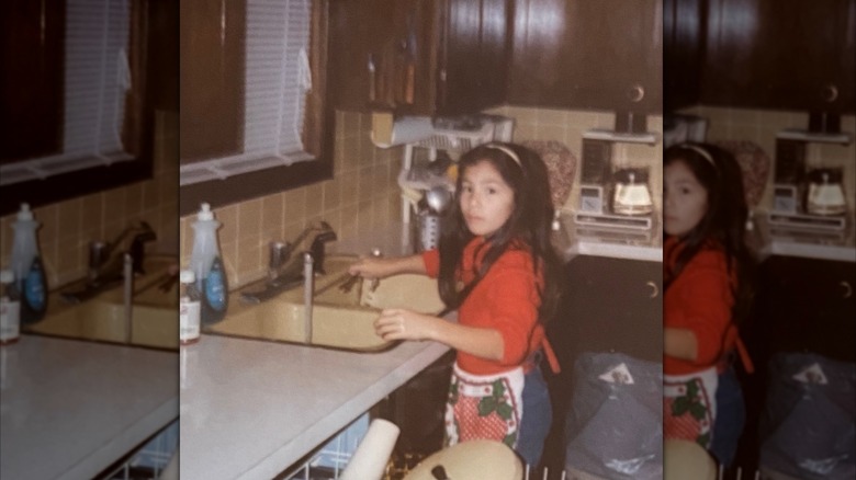 Young Joanna Gaines stands at the sink in her 1980s childhood kitchen