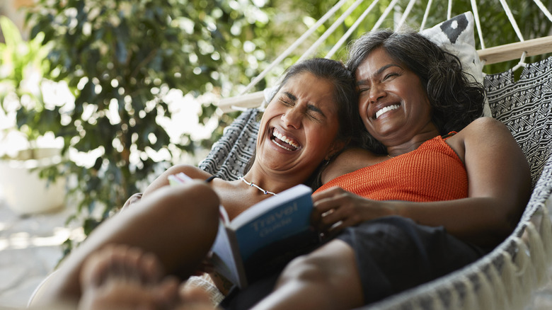 Two women lie in a hammock.