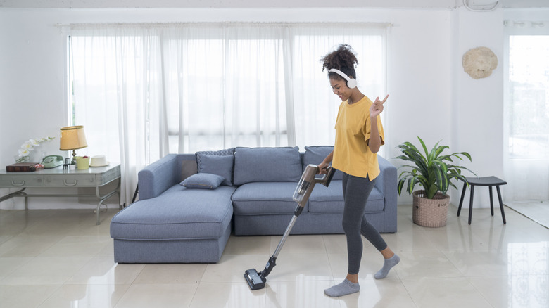 A woman vacuums the floor.