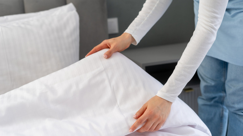 A woman makes a bed.