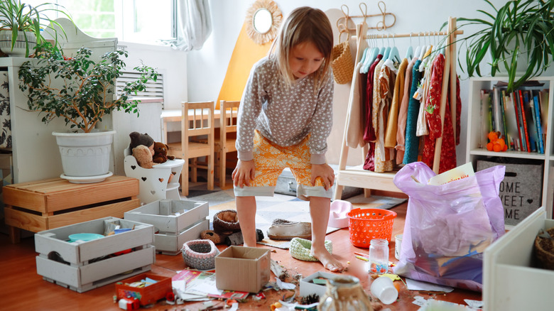 A child looking at a mess of toys.