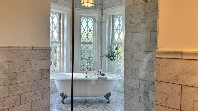 A clawfoot tub in a gray tiled wet room