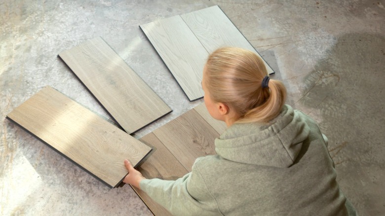 woman comparing vinyl flooring samples on bare concrete subfloor