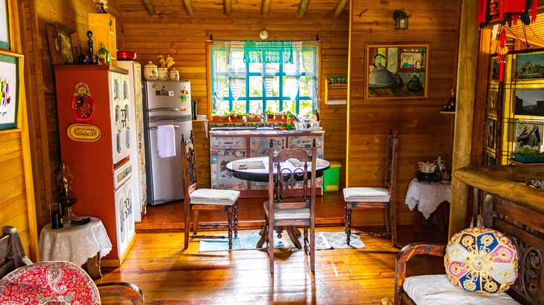 A colorful, eclectic kitchen with some built-in cabinets, freestanding storage units, and a table