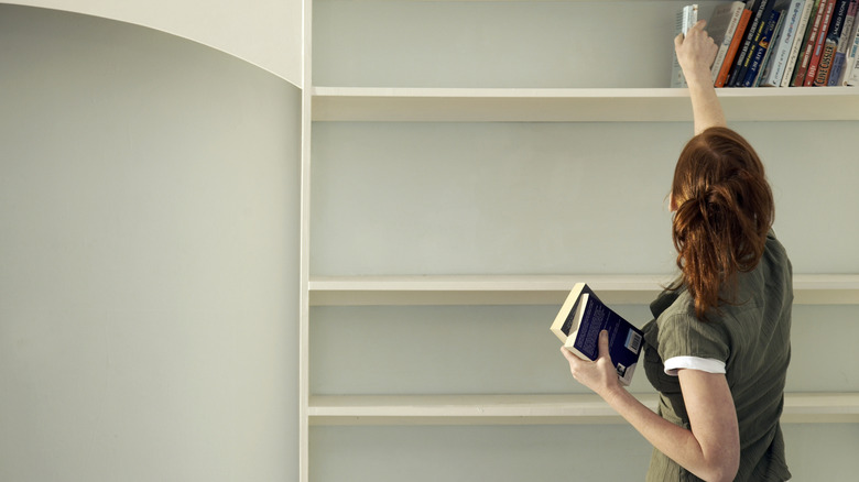 Woman putting books onto bookshelf