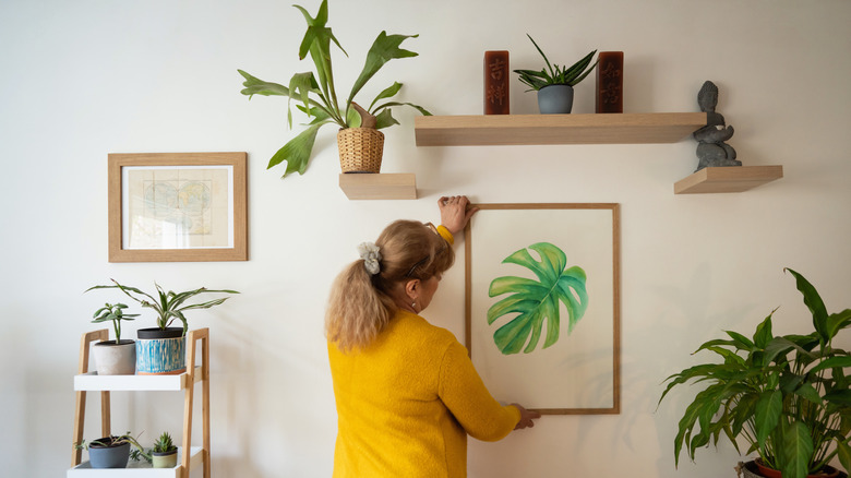 woman hanging painting on wall