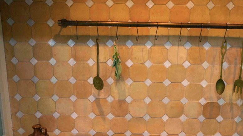 Utensils and and herb hanging on a kitchen backsplash.