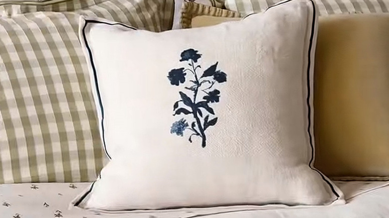 Floral and plaid pillows on a bed.
