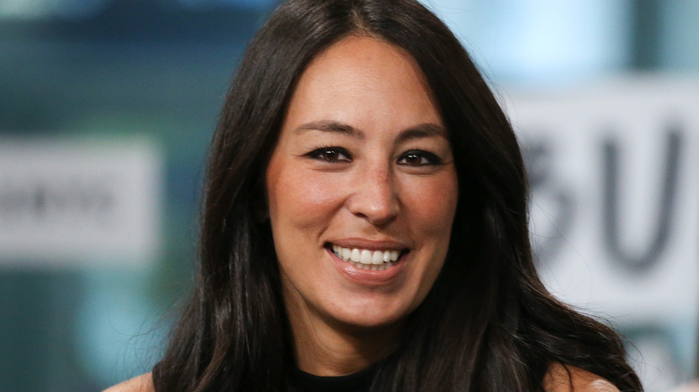 Joanna Gaines smiling in front of blurred background