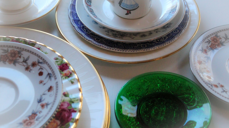 Stacks of mismatched vintage ceramic and glass plates.