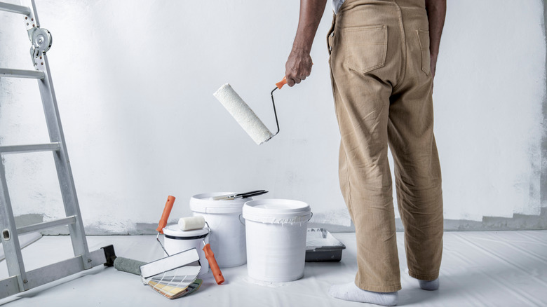 man holding white roller brush