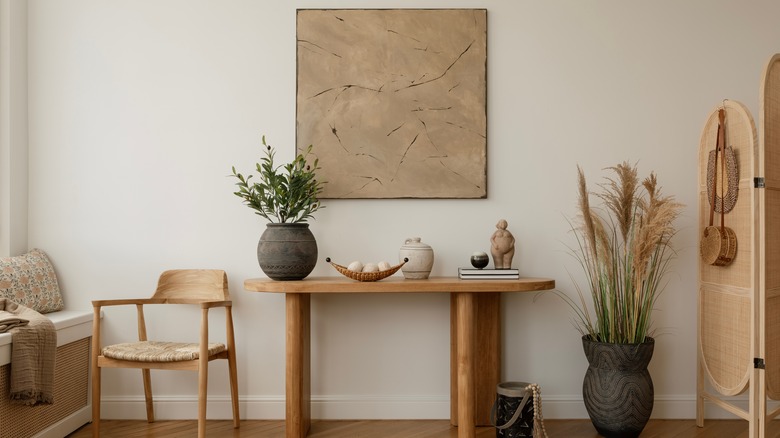 Aesthetic interior design featuring a wooden console table adorned with decorative vases, candles, and black sculptures.