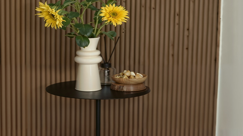 sunflower in a vase beside bowl with decorative stomes