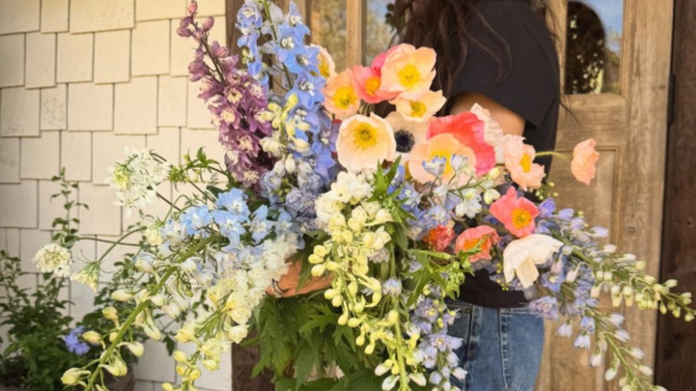 Joanna Gaines holds an oversized bouquet of poppies and delphinium on her porch.
