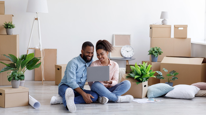 A couple shopping online in their new, undecorated home.
